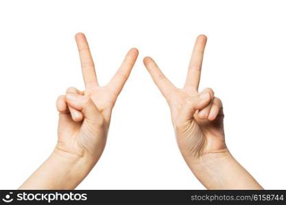 gesture and body parts concept - close up of woman hands showing peace or victory sign. close up of hands showing peace or victory sign