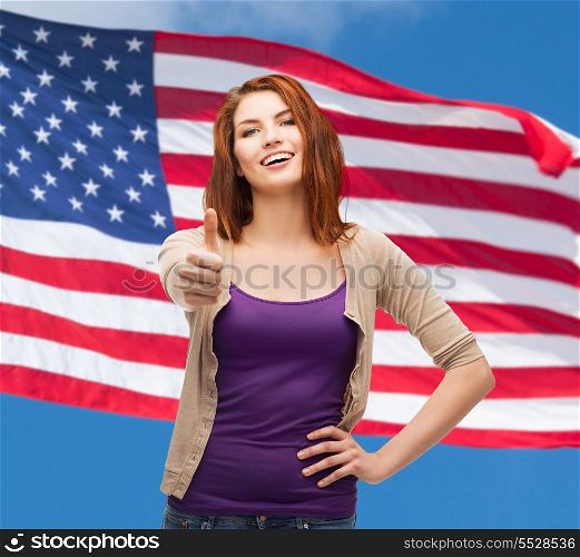 gesture and happy people concept - smiling girl in casual clothes showing thumbs up over american flag background
