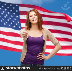 gesture and happy people concept - smiling girl in casual clothes showing thumbs up over american flag background