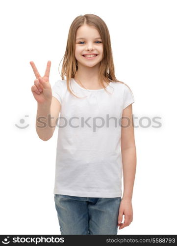 gesture and happy people concept - smiling little girl in white blank t-shirt showing peace gesture with fingers