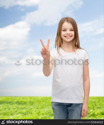 gesture and happy people concept - smiling little girl in white blank t-shirt showing peace gesture with fingers