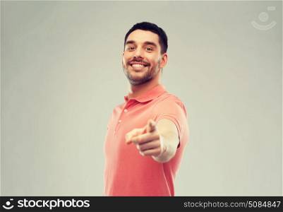gesture and people concept - happy smiling young man pointing finger to you over gray background. man pointing finger to you over gray background. man pointing finger to you over gray background