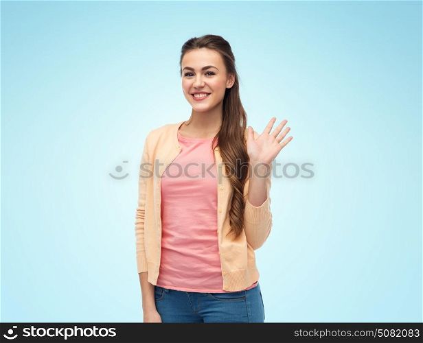 gesture and people concept - happy smiling young woman in cardigan waving hand over blue background. happy smiling young woman waving hand over white
