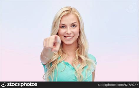 gesture and people concept - happy smiling young woman or teenage girl pointing finger to you over rose quartz and serenity gradient background. happy young woman pointing finger to you