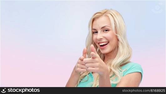 gesture and people concept - happy smiling young woman or teenage girl pointing finger to you over pink background. happy young woman pointing finger to you