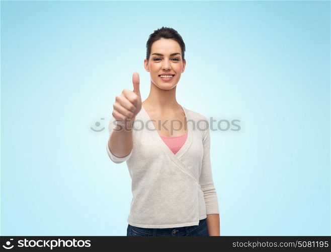 gesture and people concept - happy smiling young woman with braces showing thumbs up over blue background. happy smiling woman with braces showing thumbs up