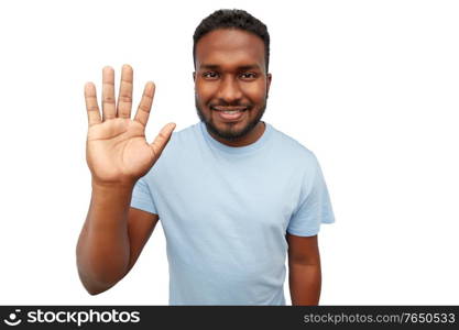 gesture and people concept - smiling african american young man waving hand over white background. smiling african american young man waving hand