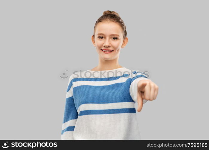 gesture and people concept - smiling teenage girl in pullover pointing finger to camera over grey background. smiling teenage girl pointing to camera