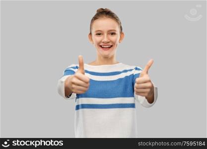 gesture and people concept - smiling teenage girl in pullover showing thumbs up over grey background. smiling teenage girl showing thumbs up