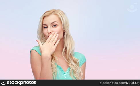 gesture and people concept - smiling young woman or teenage girl covering her mouth with hands over pink background. smiling young woman or teen girl covering mouth