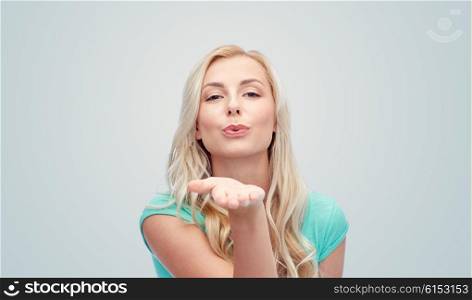 gesture and people concept - smiling young woman or teenage girl sending blow kiss over gray background. smiling young woman or teen girl sending blow kiss
