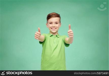 gesture, childhood, fashion and people concept - happy smiling boy in green polo t-shirt showing thumbs up over green school chalk board background