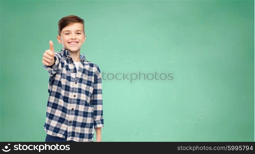 gesture, childhood, school, education and people concept - smiling student boy in checkered shirt and jeans showing thumbs up over green school chalk board background
