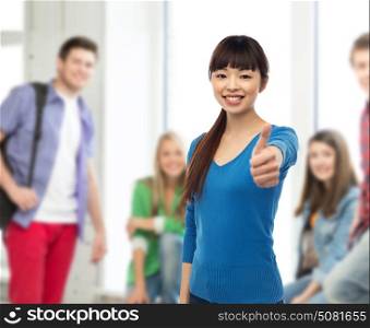 gesture, education and people concept - happy smiling young asian student woman showing thumbs up over school classroom background. happy smiling young woman showing thumbs up