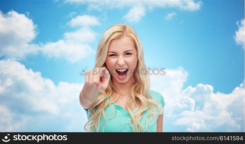 gesture, emotions, expressions and people concept - happy smiling young woman or teenage girl pointing finger to you over blue sky and clouds background