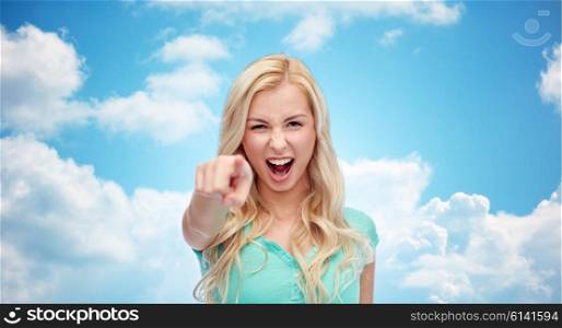 gesture, emotions, expressions and people concept - happy smiling young woman or teenage girl pointing finger to you over blue sky and clouds background