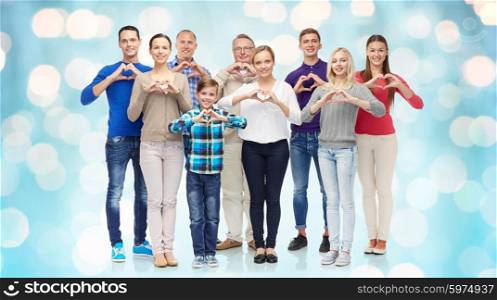 gesture, family, generation and people concept - group of smiling men, women and boy showing heart shape hand sign over blue holidays lights background