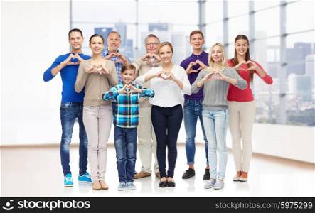 gesture, family, generation and people concept - group of smiling men, women and boy showing heart shape hand sign over empty office room or home