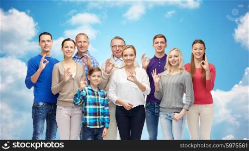 gesture, family, generation and people concept - group of smiling men, women and boy showing ok hand sign over blue sky and clouds background