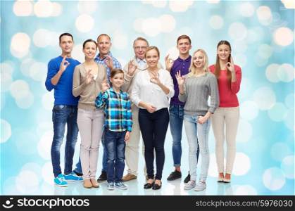 gesture, family, generation and people concept - group of smiling men, women and boy showing ok hand sign over blue holidays lights background