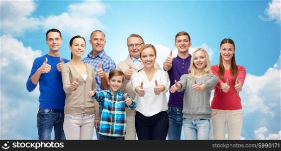 gesture, family, generation and people concept - group of smiling men, women and boy showing thumbs up over blue sky and clouds background