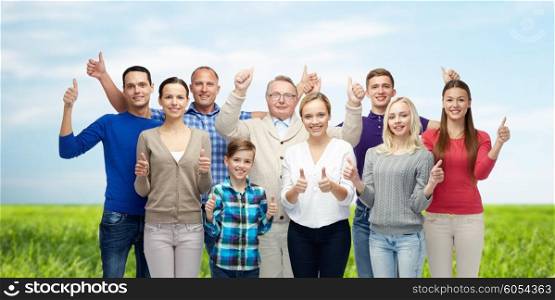 gesture, family, generation and people concept - group of smiling men, women and boy showing thumbs up over blue sky and grass background