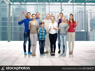 gesture, family, generation and people concept - group of smiling men, women and boy showing thumbs up over terminal with window city view background