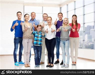 gesture, family, generation, real estate and people concept - group of smiling men and women showing thumbs up over empty apartment or office room background