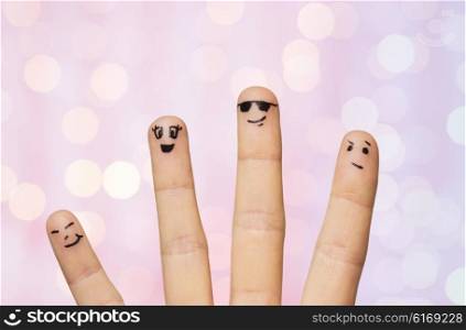 gesture, family, people and body parts concept - close up of four fingers with smiley faces over pink holidays lights background