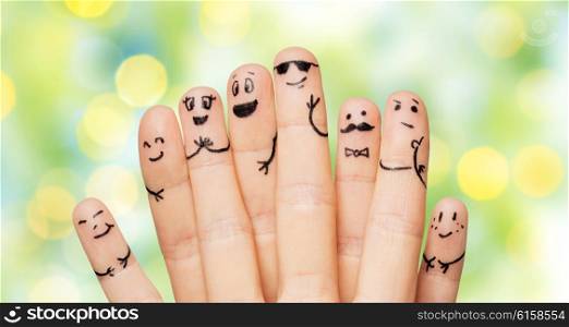 gesture, family, people and body parts concept - close up of two hands showing fingers with smiley faces over green summer holidays lights background