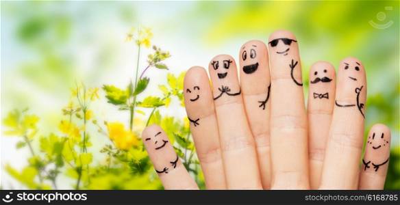 gesture, family, people and body parts concept - close up of two hands showing fingers with smiley faces over natural green herbal background