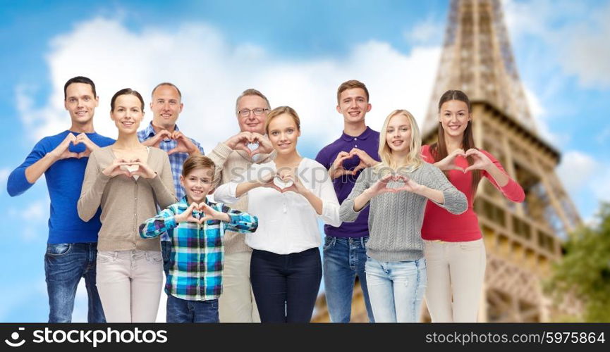 gesture, family, travel and tourism concept - group of smiling people showing heart shape hand sign over eiffel tower background