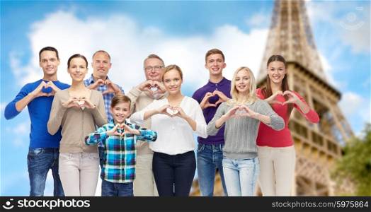 gesture, family, travel and tourism concept - group of smiling people showing heart shape hand sign over eiffel tower background