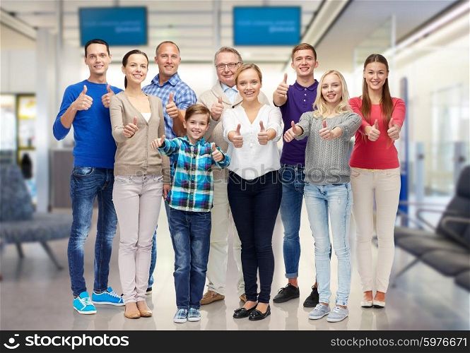gesture, family, travel, generation and people concept - group of smiling men and women showing thumbs up over airport waiting room background