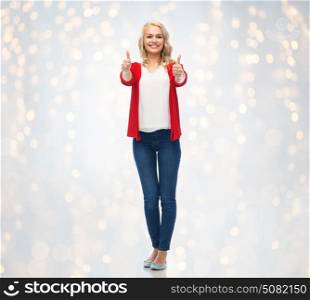 gesture, fashion and people concept - happy smiling young woman in red cardigan showing thumbs up over holidays lights background. happy smiling young woman showing thumbs up