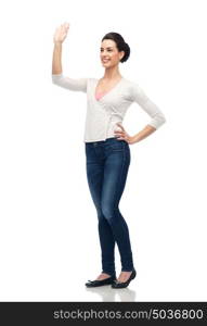 gesture, fashion, portrait and people concept - happy smiling young woman in cardigan cardigan and jeans hand over white. happy smiling young woman waving hand over white