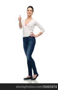 gesture, fashion, portrait and people concept - happy smiling young woman in cardigan and jeans showing thumbs up over white. happy smiling young woman showing thumbs up