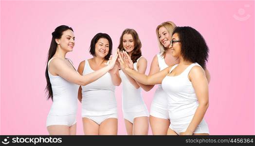 gesture, friendship, beauty, body positive and people concept - group of happy different women in white underwear making high five over pink background
