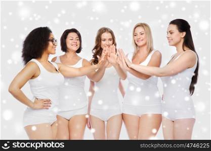 gesture, friendship, beauty, body positive and people concept - group of happy different women in white underwear making high five over snow