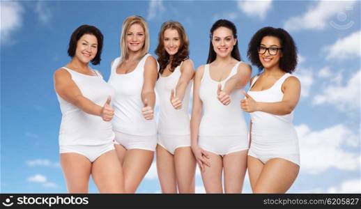 gesture, friendship, beauty, body positive and people concept - group of happy different size women in white underwear showing thumbs up over blue sky and clouds background