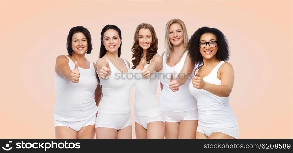gesture, friendship, beauty, body positive and people concept - group of happy different women in white underwear showing thumbs up over beige background