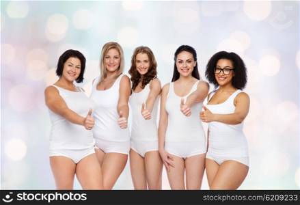 gesture, friendship, beauty, body positive and people concept - group of happy different women in white underwear showing thumbs up over holidays lights background