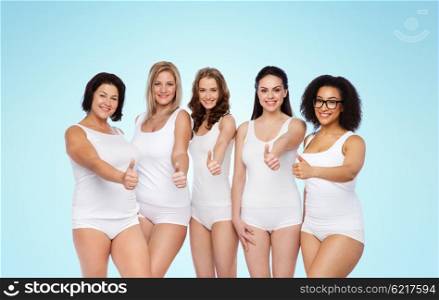 gesture, friendship, beauty, body positive and people concept - group of happy different women in white underwear showing thumbs up over blue background