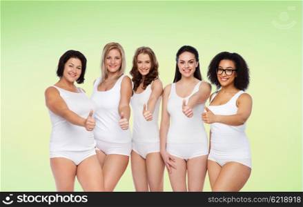 gesture, friendship, beauty, body positive and people concept - group of happy different women in white underwear showing thumbs up over green natural background
