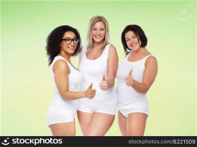 gesture, friendship, beauty, body positive and people concept - group of happy plus size women in white underwear showing thumbs up over green natural background