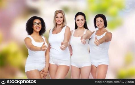 gesture, friendship, beauty, body positive and people concept - group of happy different women in white underwear showing thumbs up over natural spring background