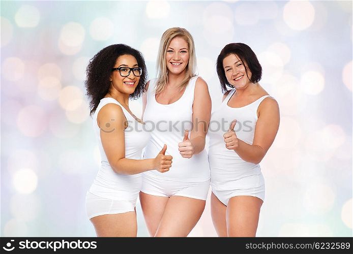 gesture, friendship, beauty, body positive and people concept - group of happy plus size women in white underwear showing thumbs up over holidays lights background