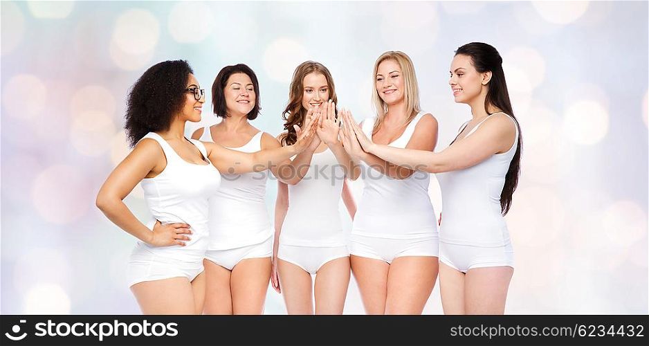 gesture, friendship, beauty, body positive and people concept - group of happy different women in white underwear making high five over holidays lights background