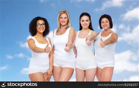 gesture, friendship, beauty, body positive and people concept - group of happy different women in white underwear showing thumbs up over blue sky and clouds background