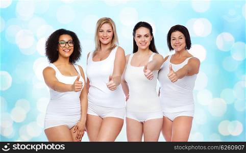 gesture, friendship, beauty, body positive and people concept - group of happy different women in white underwear showing thumbs up over blue holidays lights background